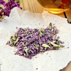 Oregano dried on paper, cup with tea, fresh oregano flowers on a wooden boards background